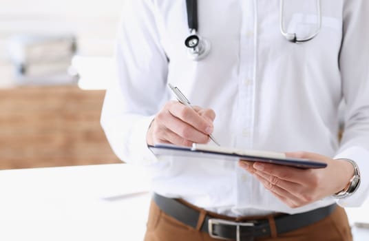 Male medicine doctor hand holding silver pen and clipboard pad closeup. Ward round patient visit check medical calculation and statistics concept physician ready to examine patient