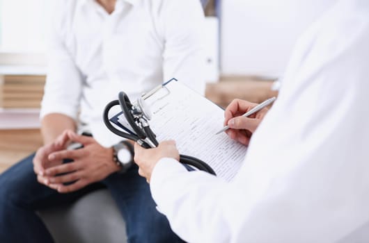 Male doctor hand hold silver pen and showing pad. Physical agreement form signature disease prevention ward round reception consent contract sign prescribe remedy healthy lifestyle concept