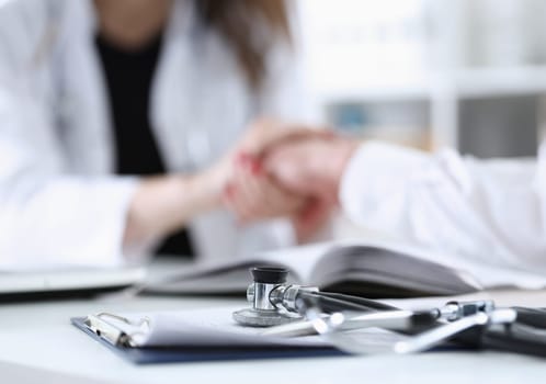 Stethoscope head lying on medical forms closeup while medicine doctor working in background. Patient history list visit check 911 medical calculation and statistics healthy lifestyle concept