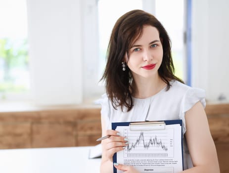 Beautiful smiling cheerful girl at workplace look in camera with colleagues group in background. White collar worker at workspace job offer modern lifestyle client visit profession train concept