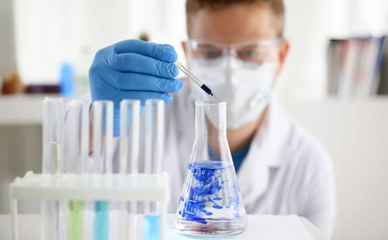 A male chemist holds test tube of glass in his hand overflows a liquid solution of potassium permanganate. Conducts an analysis of water samples versions of reagents using chemical manufacturing.