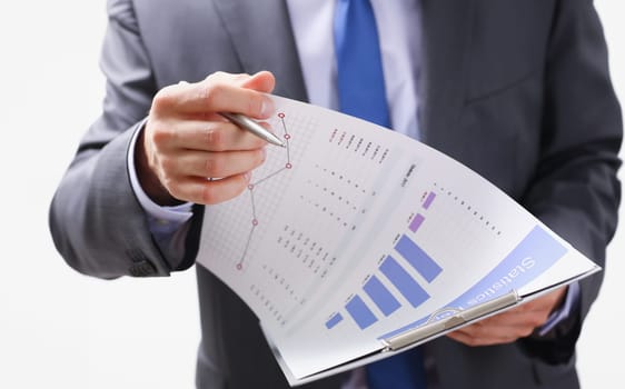 Hand of businessman in suit filling and signing with silver pen partnership agreement form clipped to pad closeup. Management training course some important document team leader ambition concept