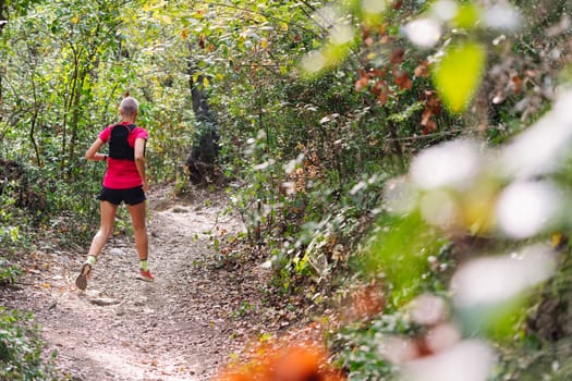 rear view of a woman practicing trail running in the forest, concept of sport in nature and healthy lifestyle, copy space for text