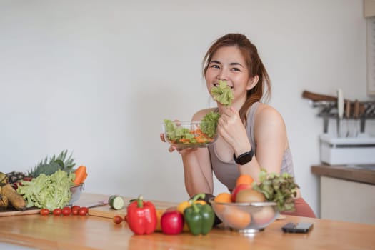 Young athletic woman is preparing a healthy organic vegetable salad in a modern kitchen at home..