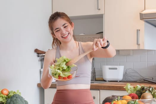 Young athletic woman is preparing a healthy organic vegetable salad in a modern kitchen at home..