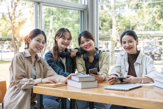 Group of cheerful Asian college students or friends laughing together while sitting in university..