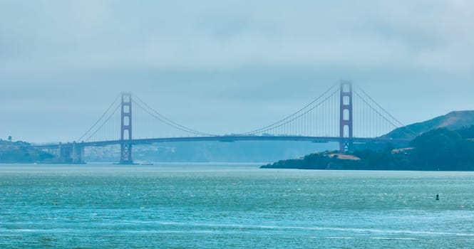 Image of Golden Gate Bridge covered in hazy fog aerial of full bridge side view