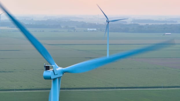 Image of In motion wind turbines on hazy morning aerial