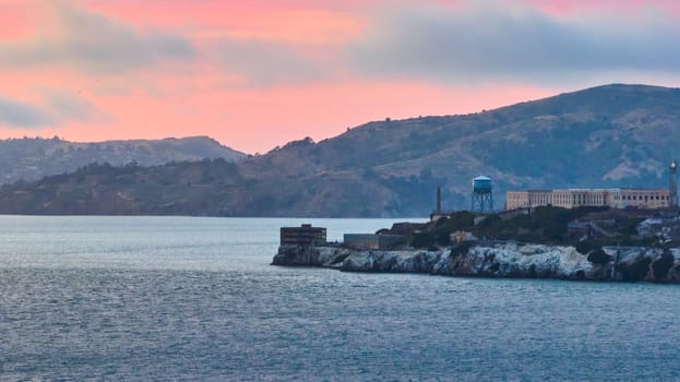 Image of Alcatraz Island with gorgeous pink and yellow sunset over blue San Francisco Bay