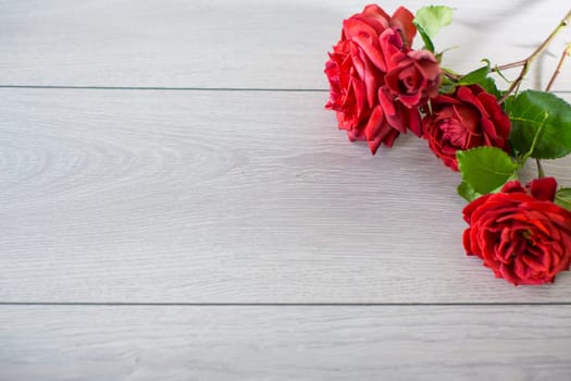 Floral background of pink, red and other roses on a light wooden table