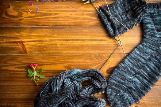 Set for hand knitting warm winter socks made of natural woolen yarn, on a wooden table.