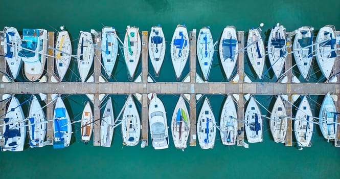 Image of Aerial straight down view row of boats on pier dock area with teal ocean water