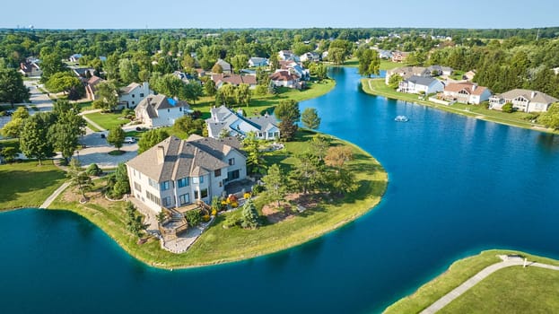 Image of Aerial rich houses next to large man made pond with water fountain