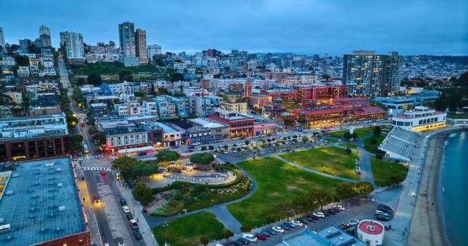 Image of Aerial green park beside bay with Ghirardelli Chocolate Experience and other city buildings at dusk