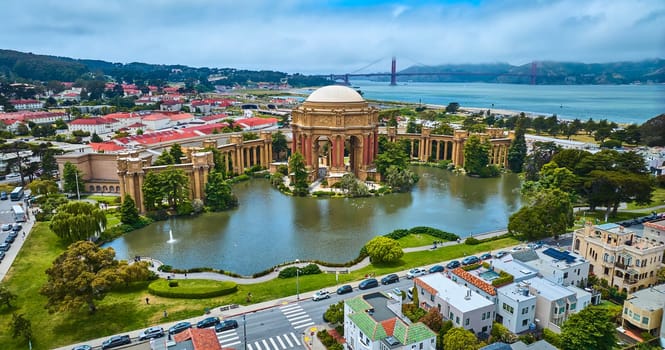 Image of Aerial Palace of Fine Arts colonnade and open rotunda on pond with city and Golden Gate Bridge