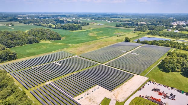 Image of High up view of solar farm in grassy field on sunny summer day