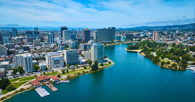 Image of Gorgeous summer day aerial over Merritt Lake with lakeside restaurant and downtown skyscrapers