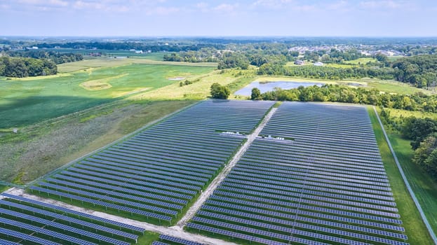 Image of Midwest solar farm aerial of solar panels in rural area with farmland and nearby swamp