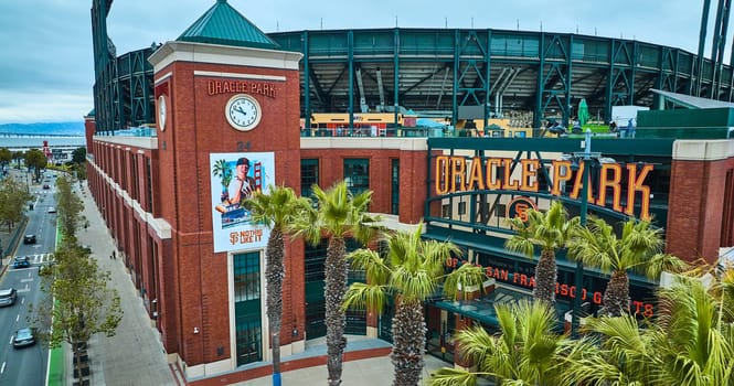 Image of Oracle Park sign with clock aerial of ballpark from above palm trees