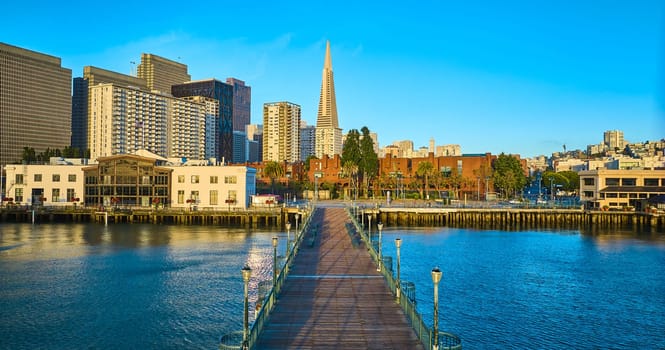 Image of Aerial over Pier 7 sunrise golden glow over city skyscrapers with blue sky