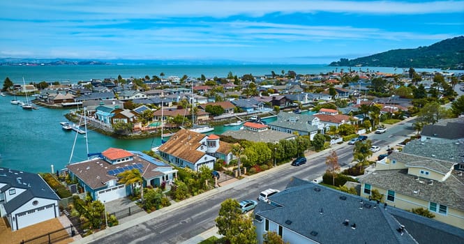 Image of Aerial over street with rich houses overlooking waterfront neighborhood with canals and boats