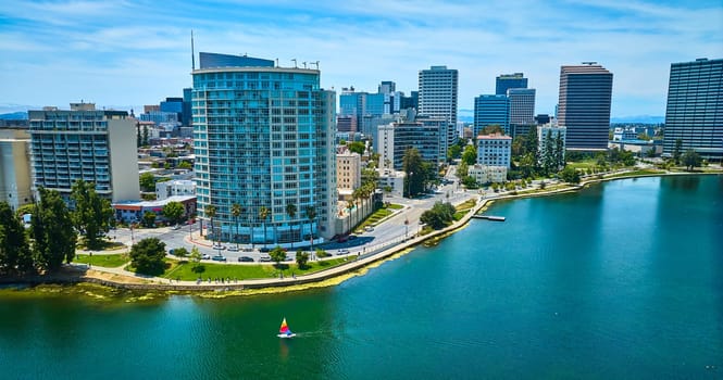 Image of Lone sailboat on Lake Merritt in front of Eastshore Properties in aerial of downtown buildings