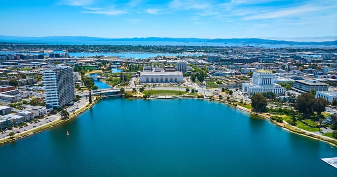 Image of Lone sailboat on Lake Merritt with apartment building and courthouse with convention center aerial