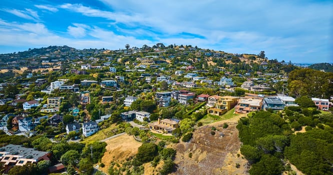 Image of Tiburon houses on hillside and city skyline with blue sky and white clouds aerial