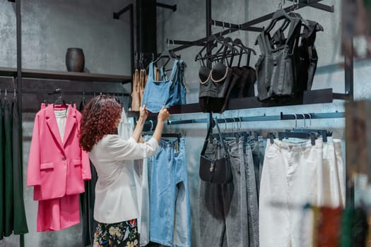 Shopping woman, women's fashion clothes in a store, boutique. Woman choosing clothes in a store.