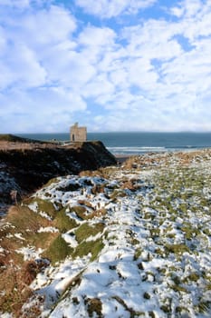 snow covered view of atlantic ocean and castle in ballybunion on a frosty snow covered winters day