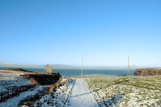 snow covered view of atlantic ocean and castle in ballybunion on a frosty winters day
