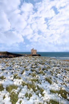 snow covered view of atlantic ocean and castle in ballybunion on a frosty snow covered winters day