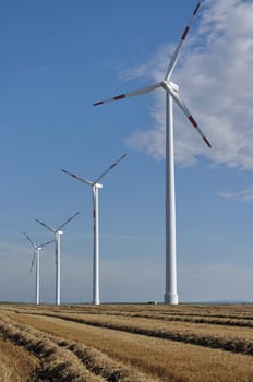 group of wind power units in corn and stubble flieds, german plains of saxony
