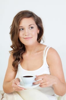 Pretty young woman waken up and having coffee in her bed