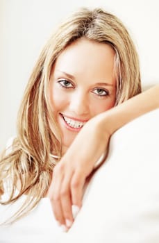 Indoor portrait of pretty young woman sitting on white couch