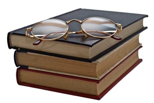 Old books and a pair of glasses isolated over a white background.