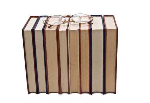 Old books and a pair of glasses isolated over a white background.