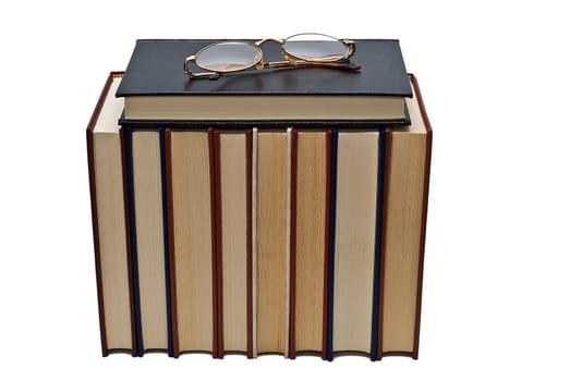 Old books and a pair of glasses isolated over a white background.