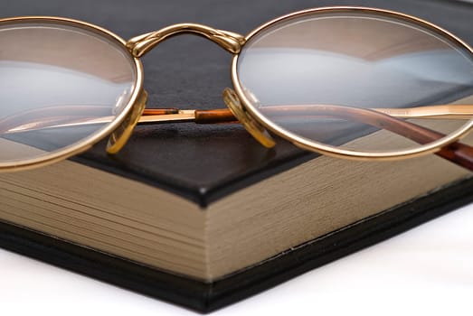 Old books and a pair of glasses isolated over a white background.