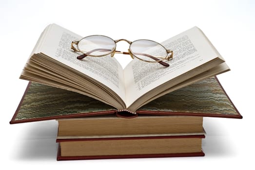 Old books and a pair of glasses isolated over a white background.