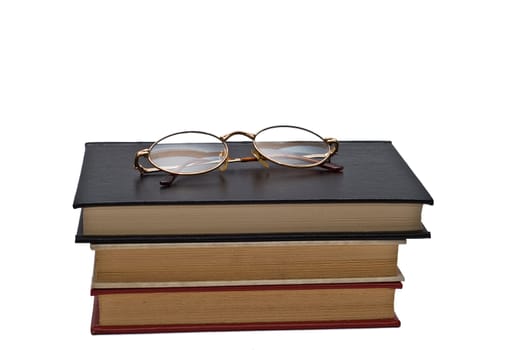 Old books and a pair of glasses isolated over a white background.