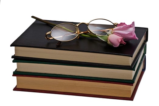 Old books and a pair of glasses isolated over a white background.
