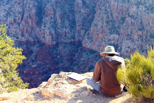 An old drawing man on the border of the Grand Canyon