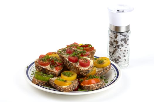 A plate of wholemeal bread topped with tomatoes and a salt and pepper mill. A plate of tomato sandwich on wholemeal bread and salt and pepper mill.
