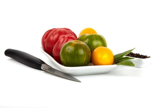 Schale mit verschiedenen frischen Bio Tomaten und einer einem Schälchen mit Pfefferkörnern und Gemüsemesser. Bowl with a variety of fresh organic tomatoes and a dish with a vegetable knife and pepper.
