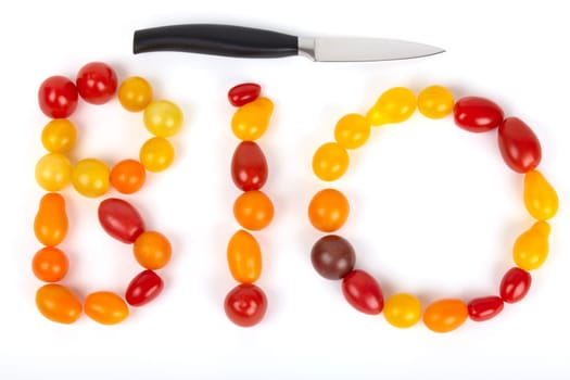 The lettering BIO is made of small colorful organic tomatoes with a knife on the side of the head. The word "organic"" set of small colored organic tomatoes with a knife on the head side."