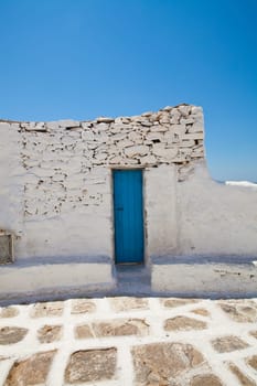 Blue wooden door on a white wall with blue sky, in Mykonos, Greece
