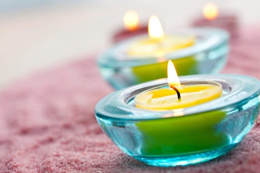 Close-up of yellow candles in glass holders on pink sand