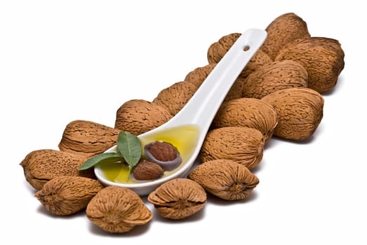 Almonds and a spoon with its oil over a white background.