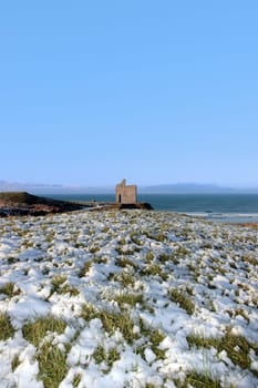 snow covered view of atlantic ocean and castle in ballybunion on a frosty snow covered winters day